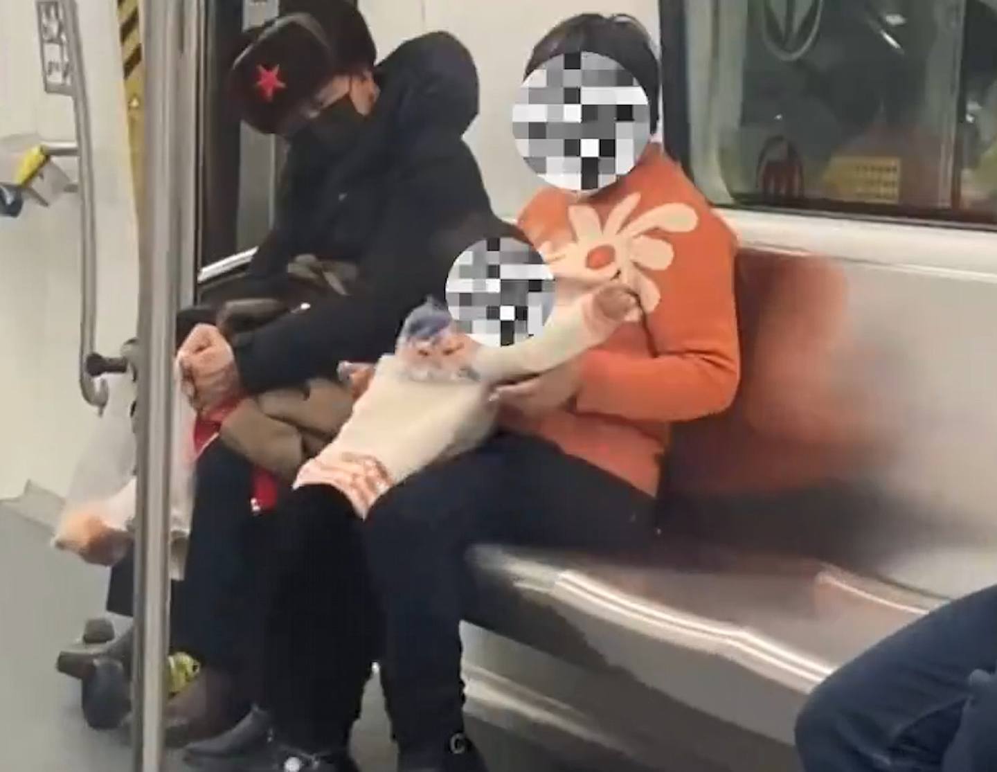 有杭州网民拍到大妈带小孩坐地铁时拉低口罩抽烟，还帮小孩点了一根烟。 （微博影片截图