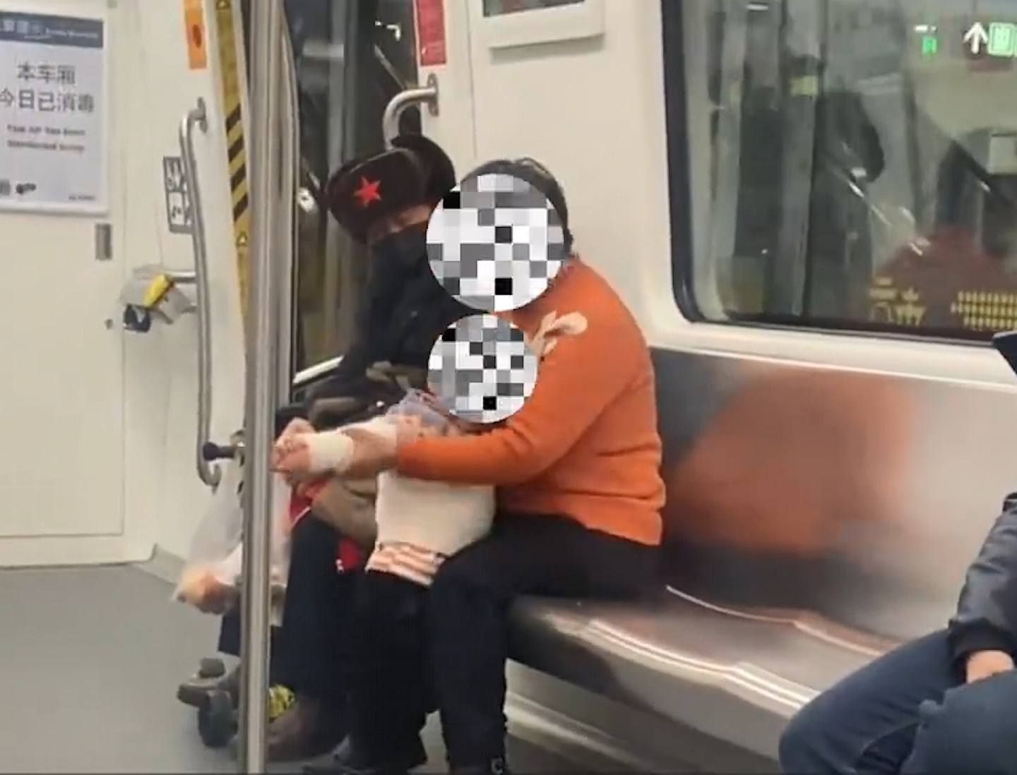 有杭州网民拍到大妈带小孩坐地铁时拉低口罩抽烟，还帮小孩点了一根烟。 （微博影片截图