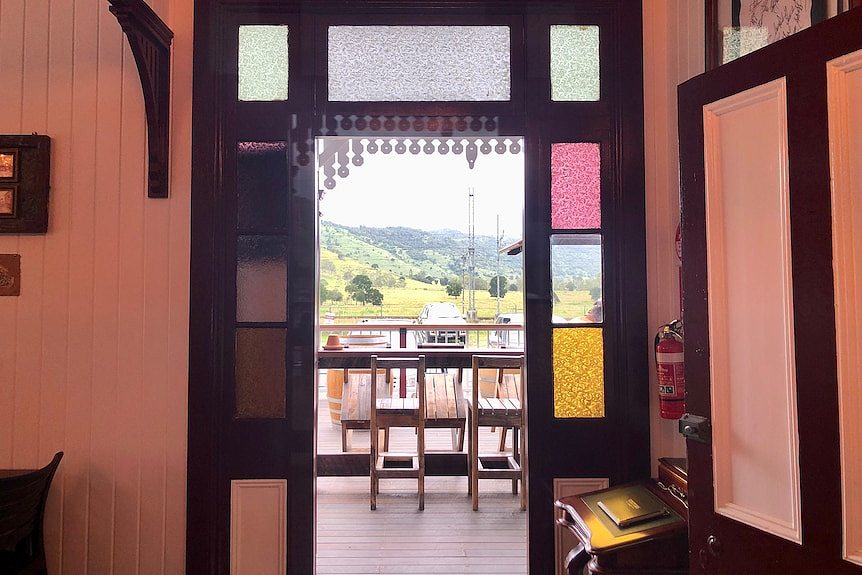 Looking out past the coloured glass panels beside the doors over the deck to mountains in the distance.