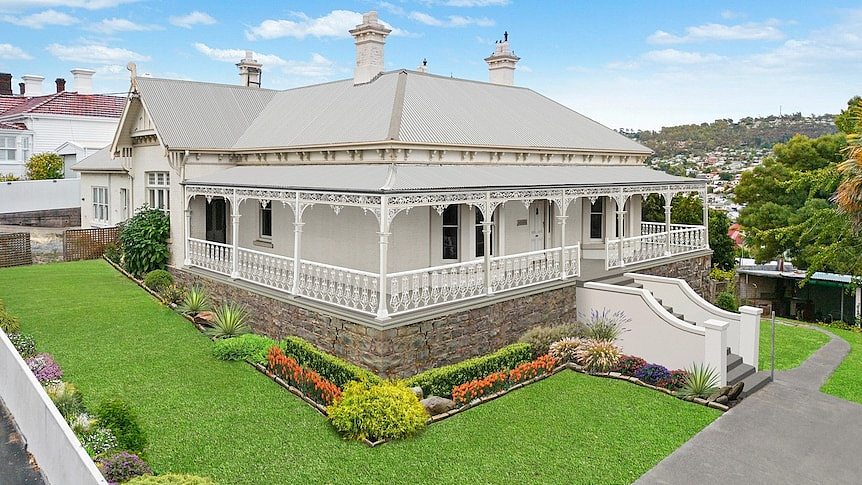 A white federation style house with a verandah