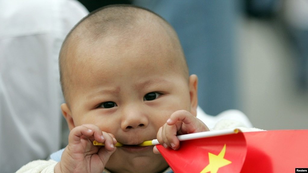 资料照：一个中国幼儿手拿一面中国国旗。