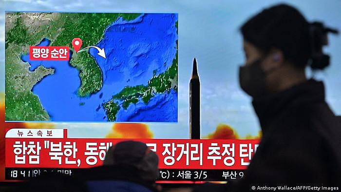 18日朝鲜试射导弹后，一名女子走过南韩报道此事的电视墙新闻画面