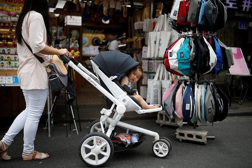A woman pushes her baby in a stroller while she shops