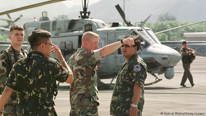 图为美国部队在菲律宾安吉利斯市的克拉克空军基地，向一名菲律奔驰兵介绍美国直升机的夜间飞行能力。