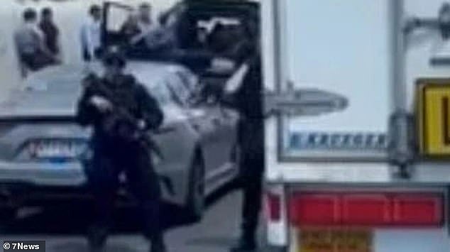 A woman has been arrested by machine gun-wielding cops (pictured) after she allegedly opened fire with a gelblaster gun at another vehicle on the M1 motorway