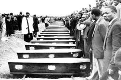 A group of people standing around caskets remembering victims