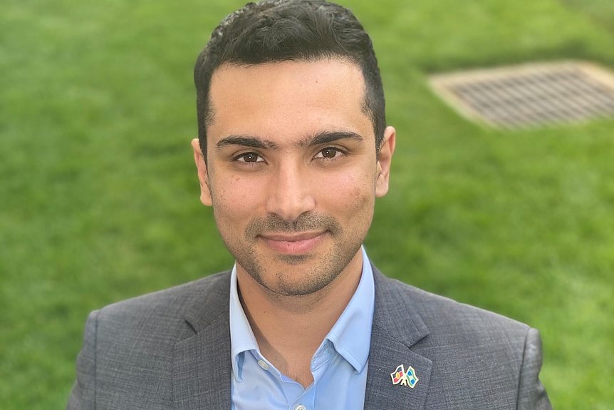 A head and shoulders shot of a man with a field of grass in the background