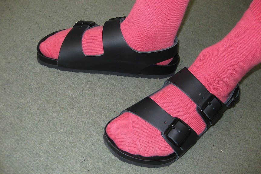 two feet wearing pink socks and black sandals