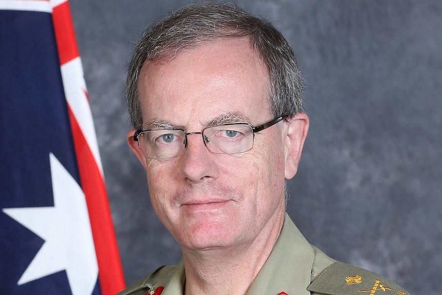 Major General Brereton's official portrait, in uniform and posed in front of an Australian flag. He's wearing glasses.