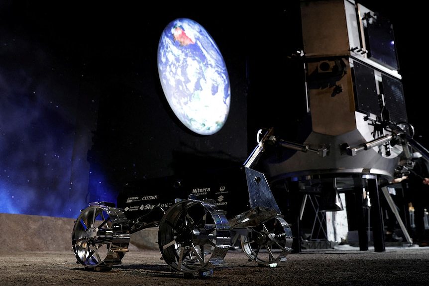 A space craft with three wheels and a photo of the earth in the background and a large rocket-like device beside it