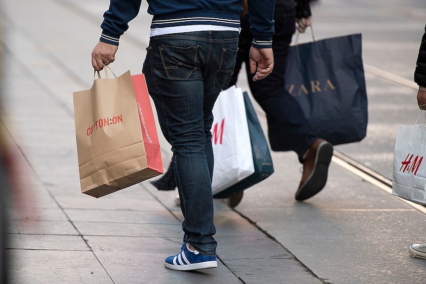 Person holding shopping bags, legs only