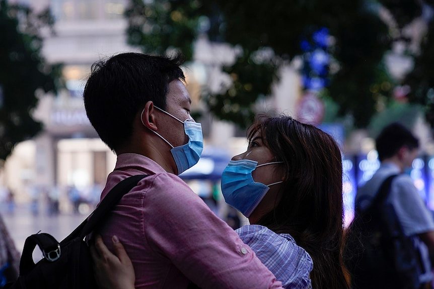 Chinese couple posing in public wearing masks