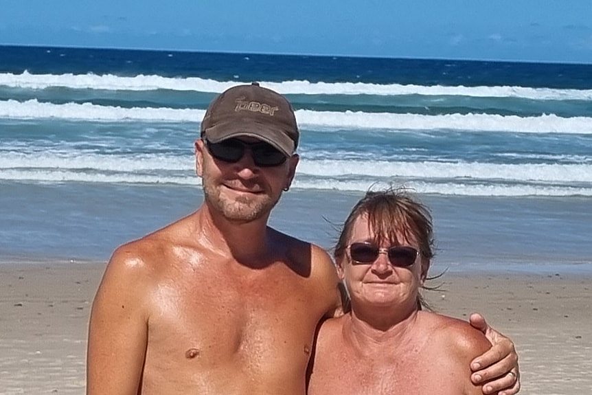 一个裸体男人站在海滩上，他的胳膊搂着一个裸体女人。