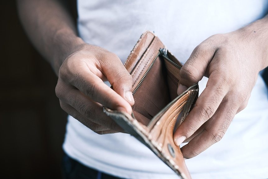 A man holds open an empty wallet.