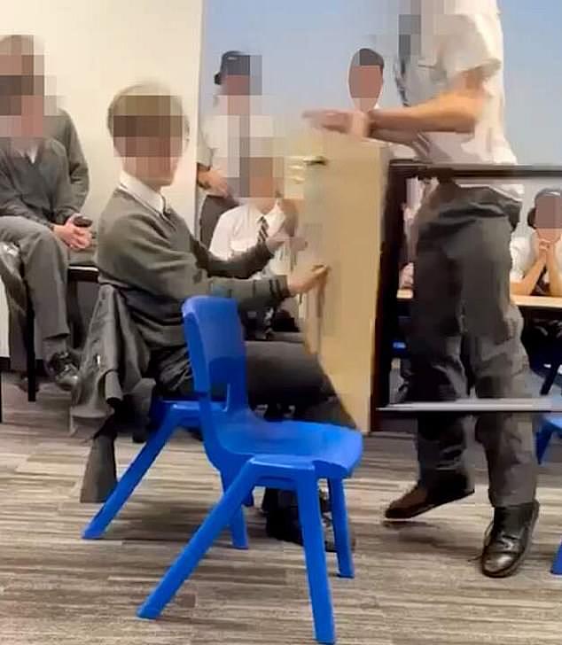 视频中可以看到一名学生捡起桌子并向另一个男孩扔