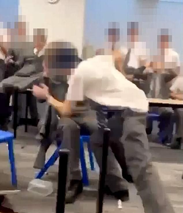 在椅子上的男孩被桌子边缘击中头部后，袭击者随后试图在他还坐着的时候对付他，引发了一场斗争（如图所示）