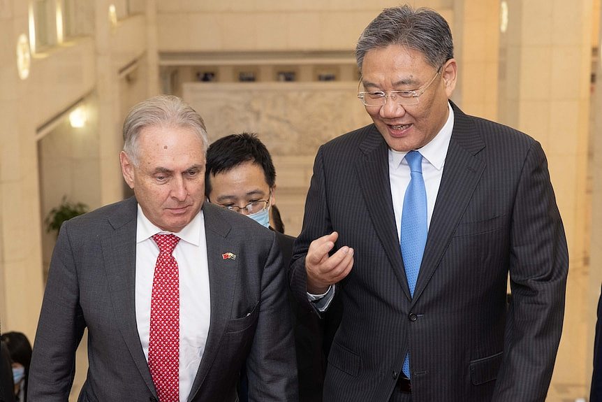 Trade Minister Don Farrell (L) and Chinese counterpart Wang Wentao (R) speaking while going up stairs.