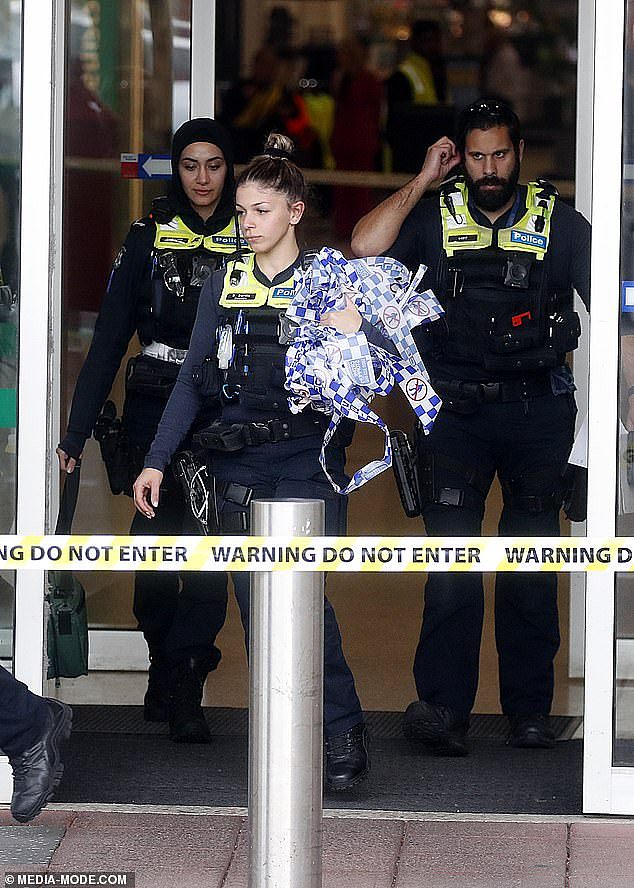 A 55-year-old woman is in critical condition after she was stabbed at Centrelink in Airport West, Melbourne (pictured, police emerge from the Centrelink)