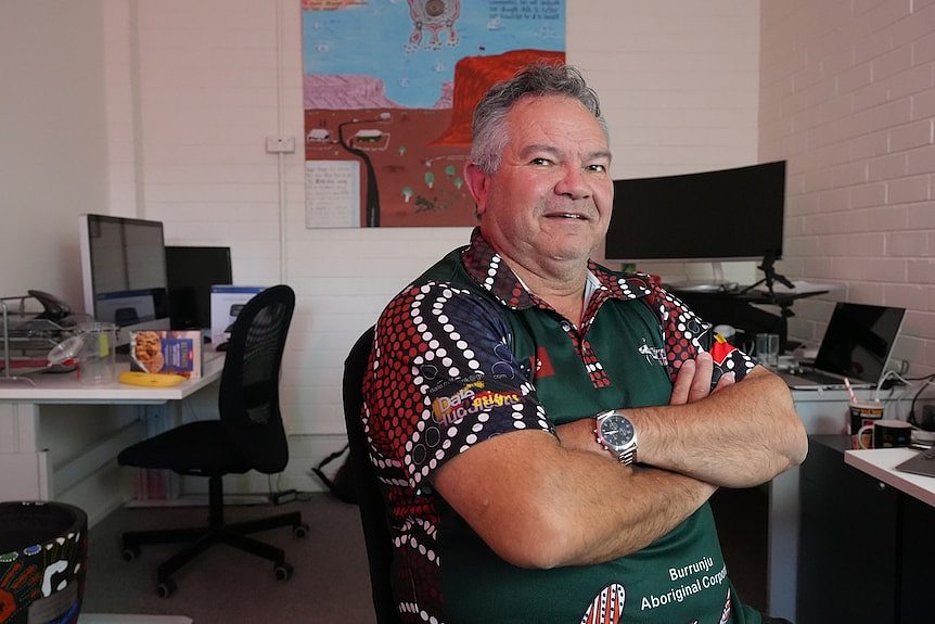 A man with his arms crossed in an office. 