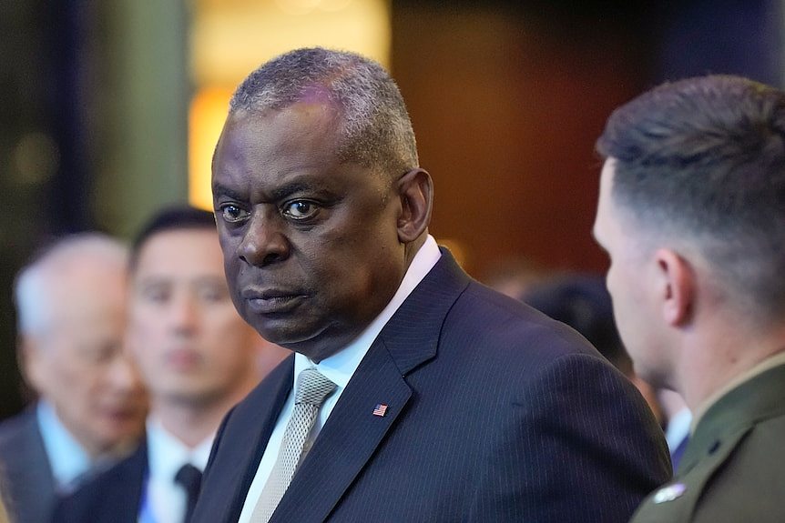 Lloyd Austin in a suit and tie stands at a dinner in Singapore