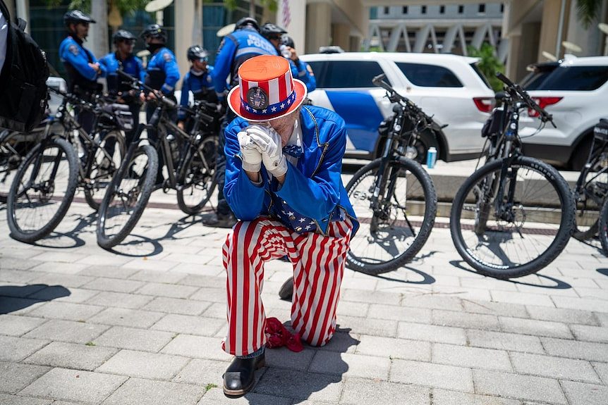 A man dressed as Uncle Sam kneels in prayer