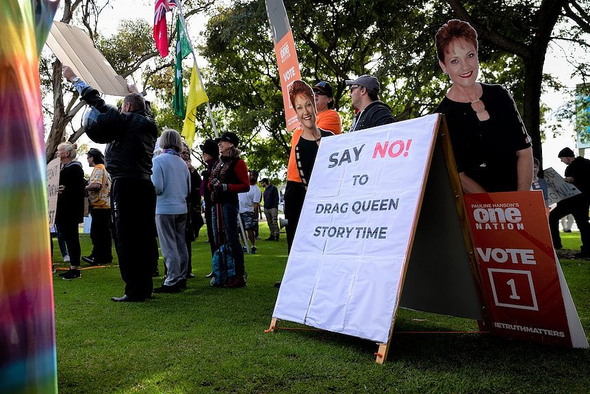 A cardboard cut-out of Pauline Hanson sits among a small group of people rallying against a drag time story event.