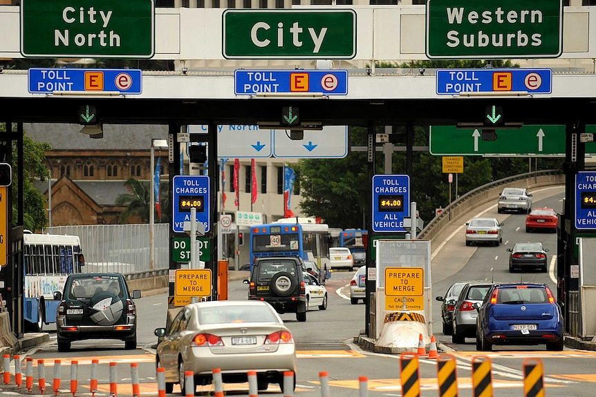 Cars on a road leading into Sydney, with toll signs above saying city north, city and western suburbs.