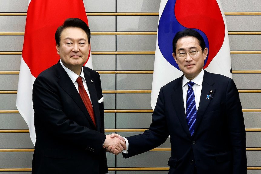South Korean President Yoon Suk-yeol, left, shakes hands with Japanese Prime Minister Fumio Kishida.