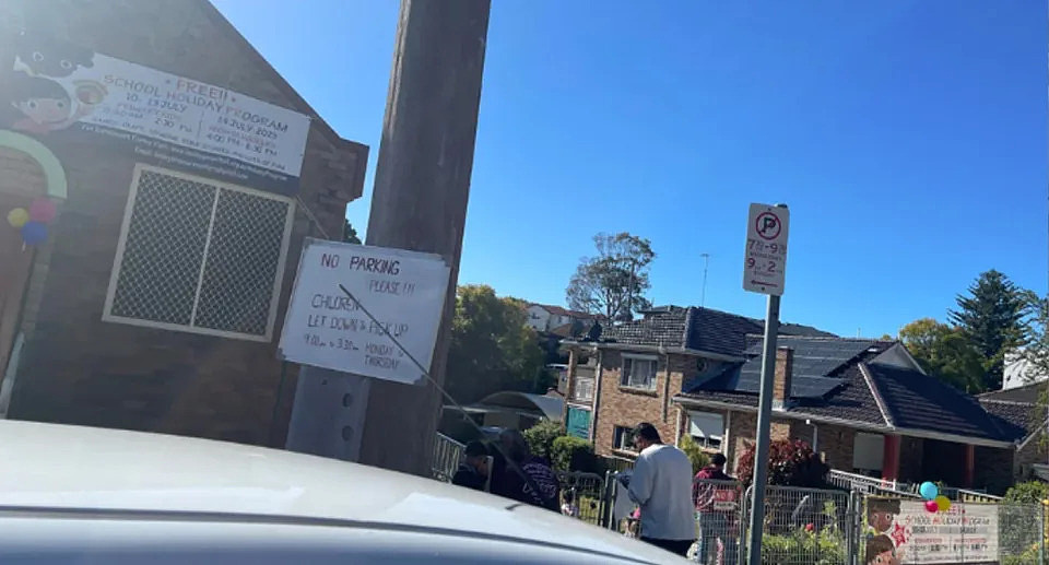 The parking sign can be seen near the church with banners advertising a daycare program during the school holidays. 