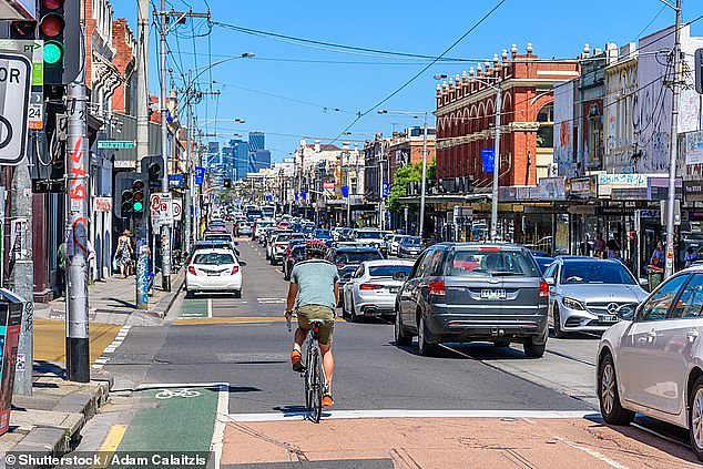Cyclists weave in between parked and parked cars when using Melbourne's iconic Sydney Road