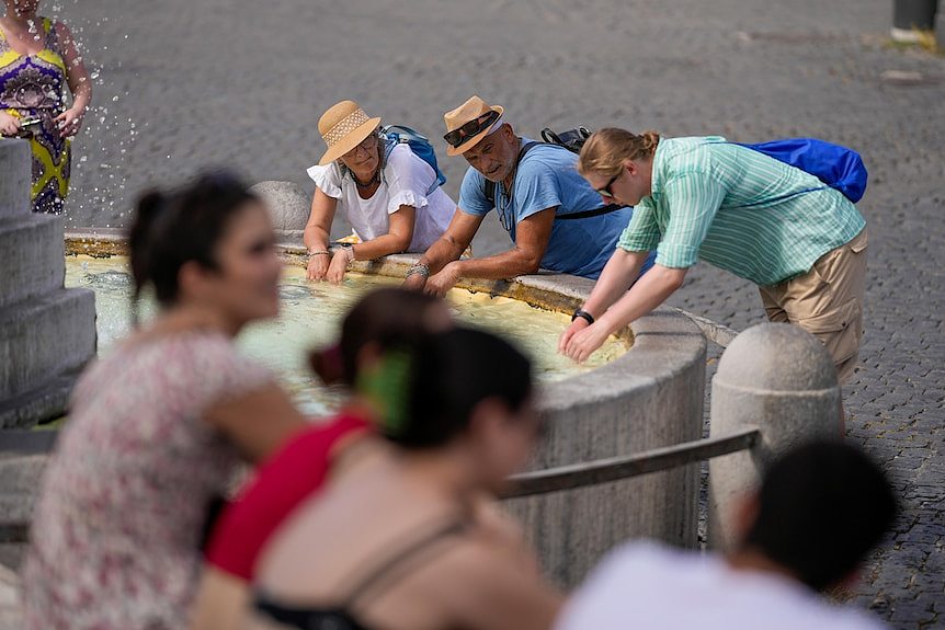 A group of tourists wash their hands in a fountain in Rome