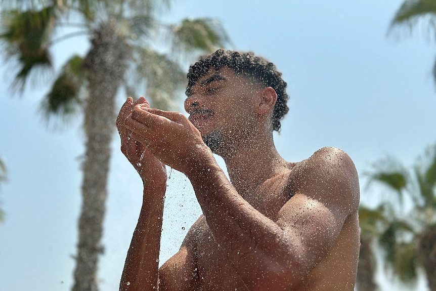 在中东迪拜，天气炎热，男子在海滩上淋浴。