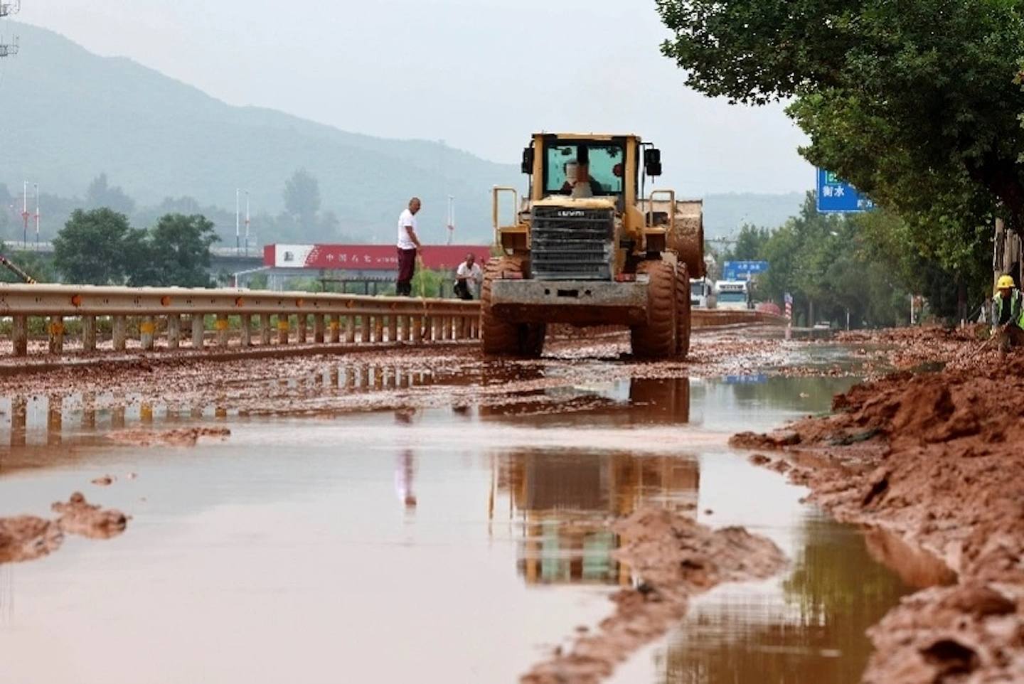 7月31日，在河北省井陉县307国道长岗村段，防汛工作人员驾驶机械清理淤泥。 （新华社）
