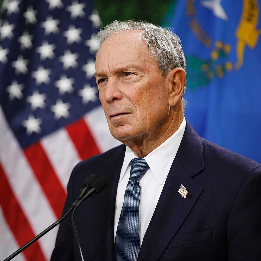 US billionaire Michael Bloomberg stands in front of an American flag.