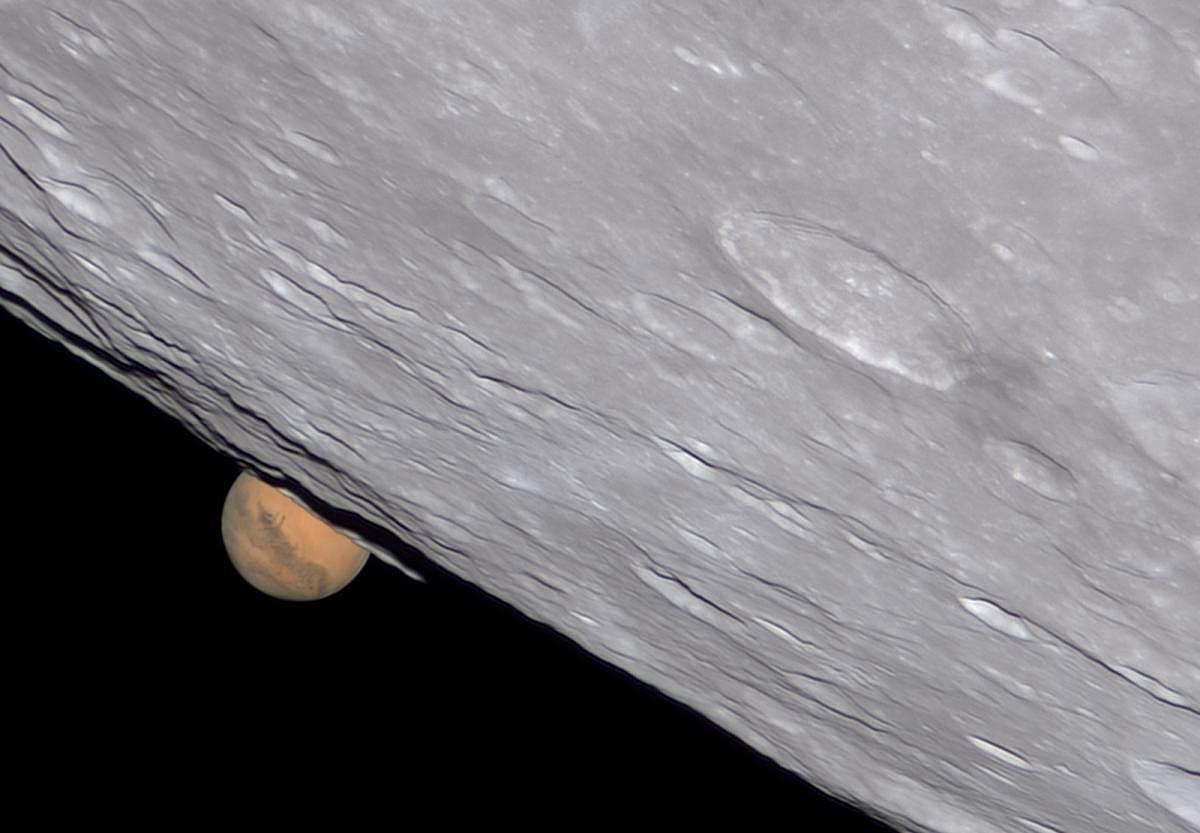 The moon passing in front of the planet Mars.