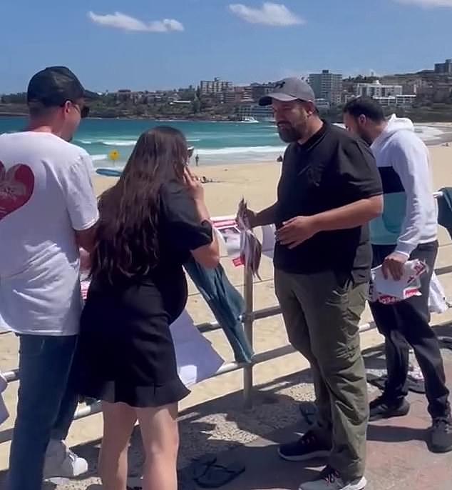 Footage shows two men approach the display, which had been approved by the local council and police, and begin tearing down the posters as organisers confronted them