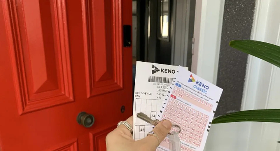 Keno ticket held up in front of new house with house keys. 