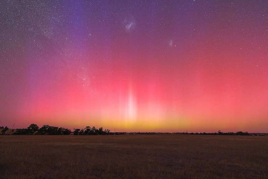Purple, pink, red, and orange aurora australias in the night sky.