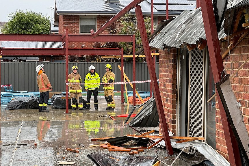 Emergency workers surveying damage to a house.