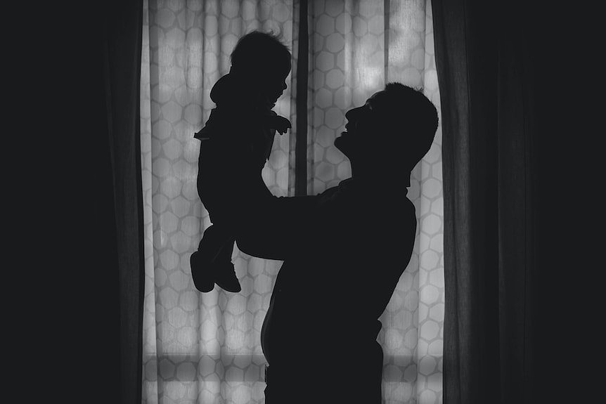 一个男人在橱窗前抱着婴儿的剪影