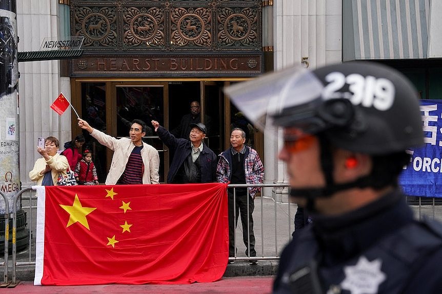 亲北京的社区成员举着中国国旗。
