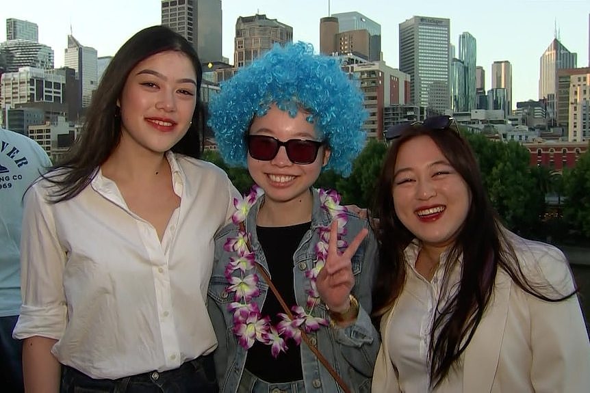 Three women smile for the camera with the Melbourne skyline behind them