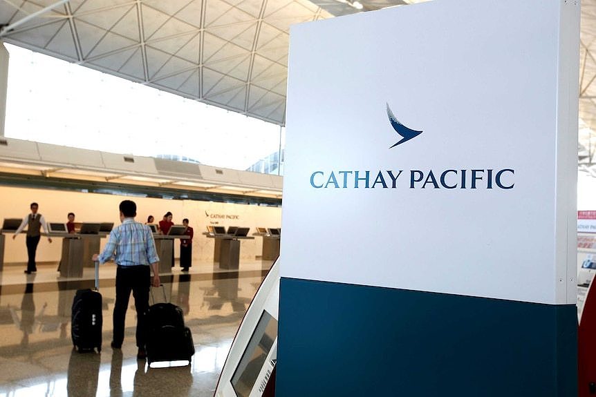 A passenger with suitcases walk up to the counter of Cathay Pacific.