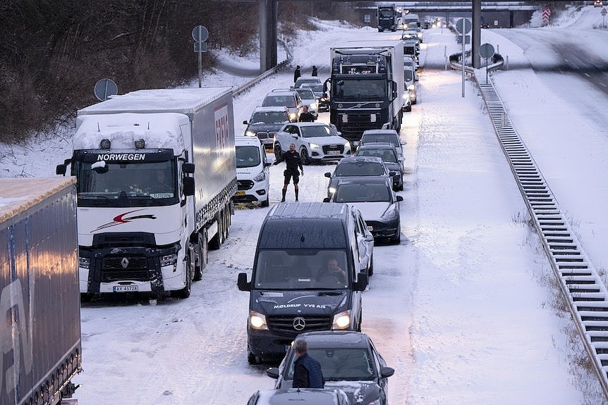 Trucks and cars are stopped in a traffic jam on a snow covered motorway in Finland
