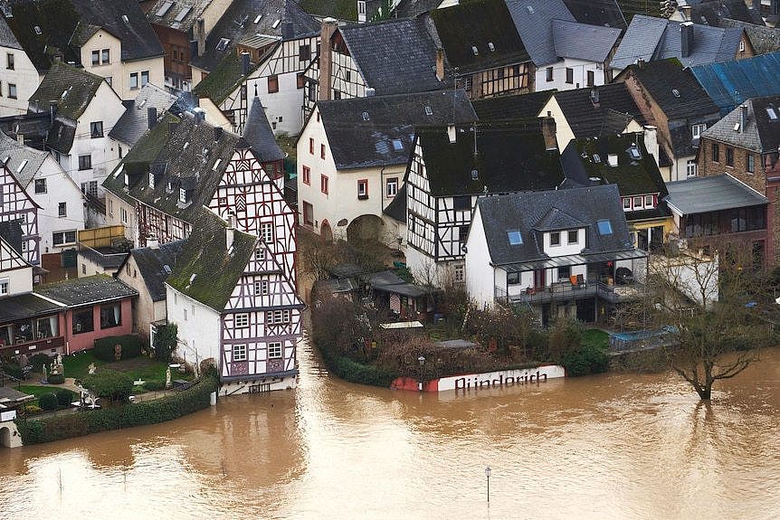 An aerial view of brown floodwater surrounding buildings in Germany