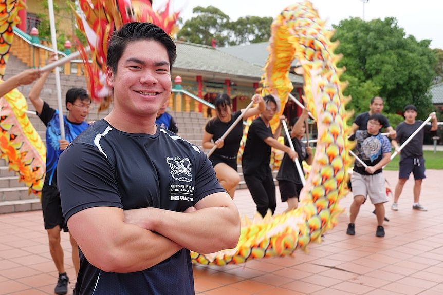A man stands in front of a dancing dragon dance team