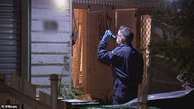 A forensic police officer examines the house on Friday night. It is understood the woman's two teenage sons were at the property and they are being cared for by neighbours