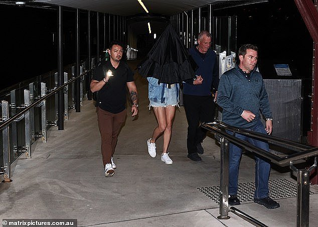 Police confirmed they were investigating claims Scott Swift, 71, allegedly assaulted a photographer. Taylor is pictured under the umbrella, next to her father Scott (right) last night