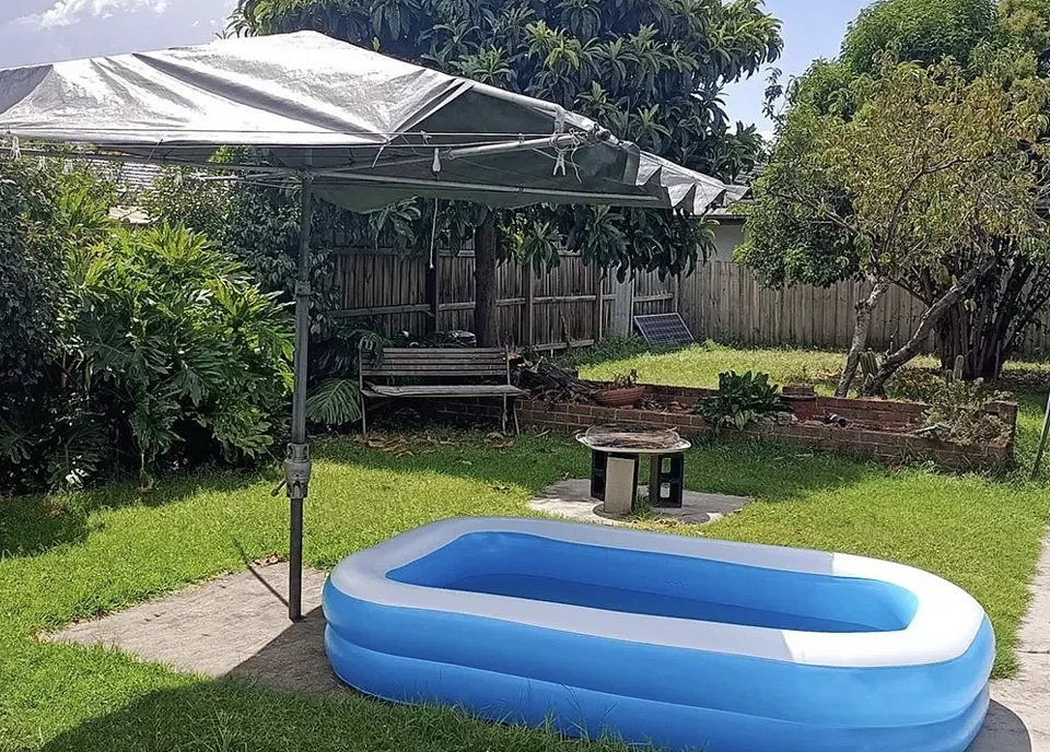 A baby pool outside under a clothes line.