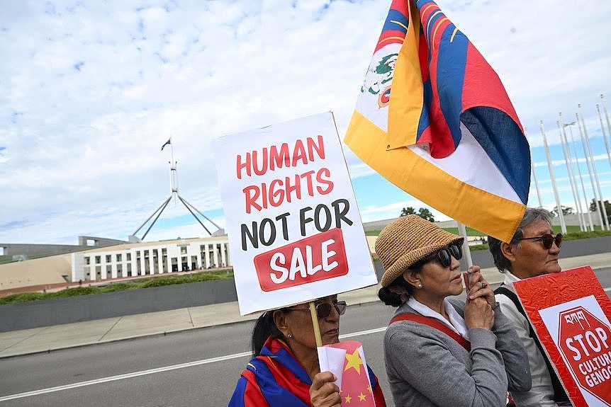 在堪培拉国会大厦前，示威者举着“人权是非卖品”的标语牌。